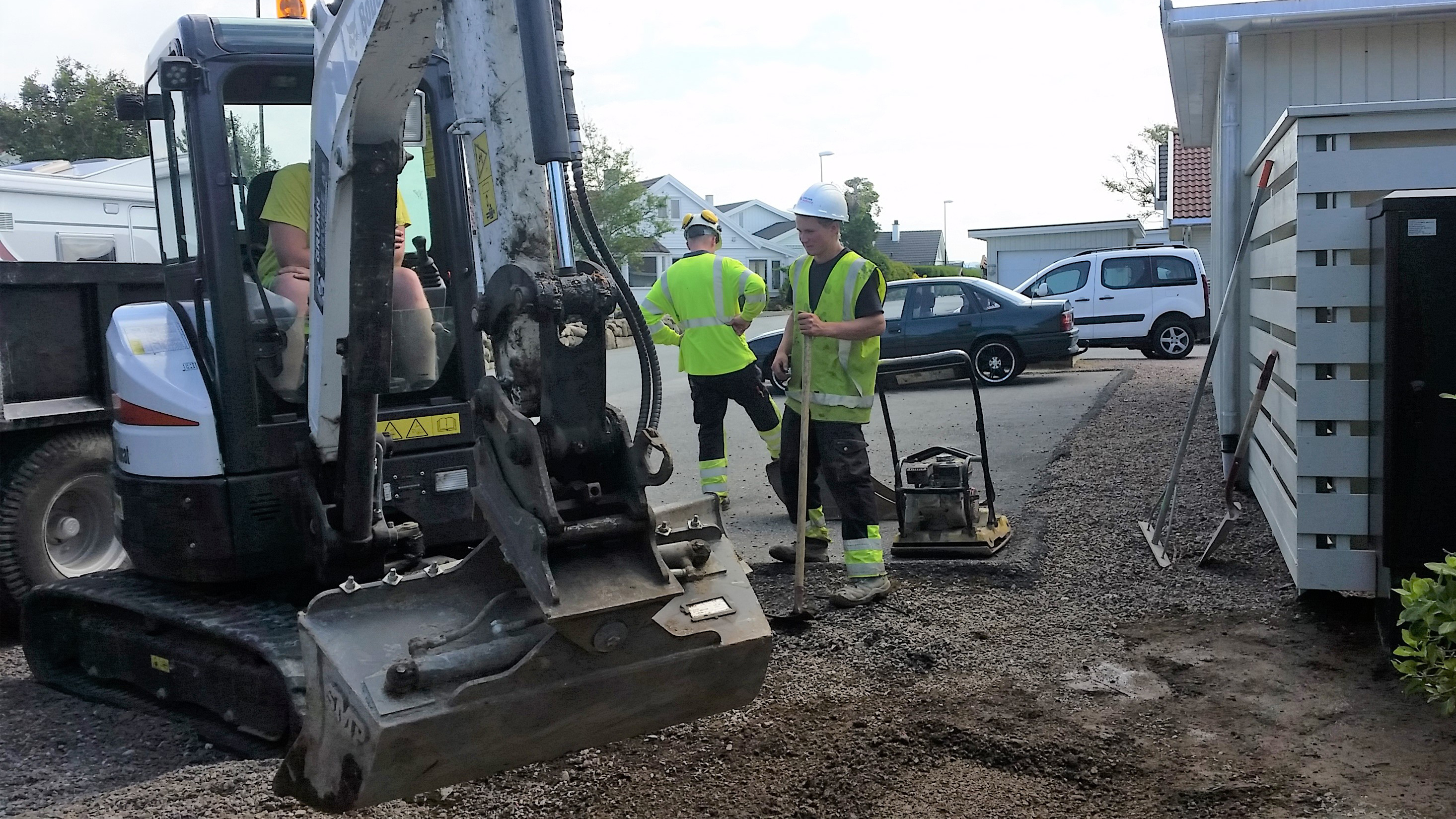 Alt=gravemaskin som arbeid i en gate og 2 håndmenn